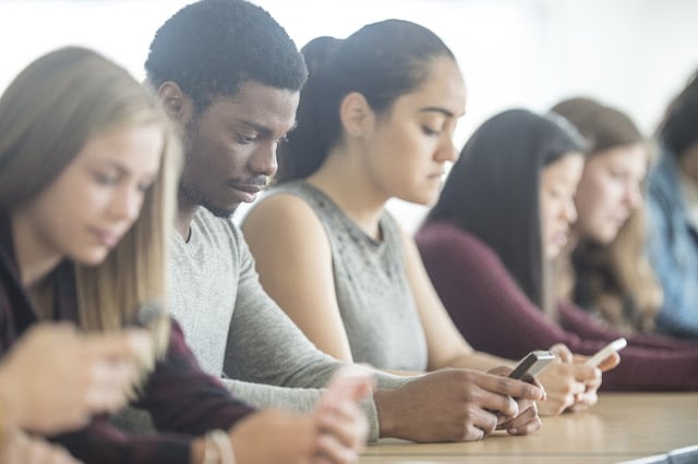 A group of students distracted by smartphones in class